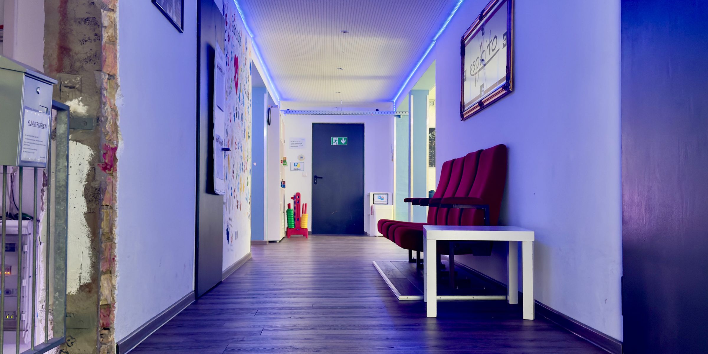 Flur des Jugendzentrums mit Sitzmöglichkeiten und blauen Deckenlichtern