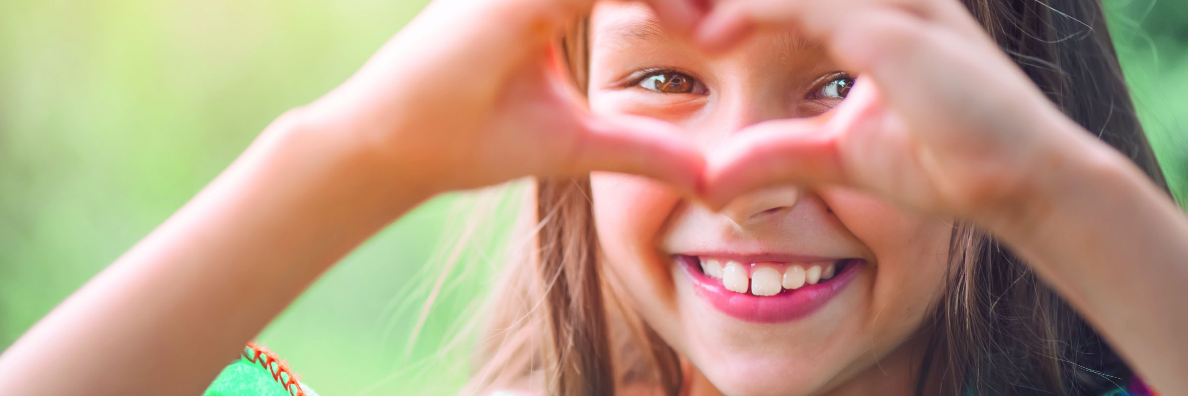 Ein lachendes Mädchen, was ihre Hände zu einem Herz formt