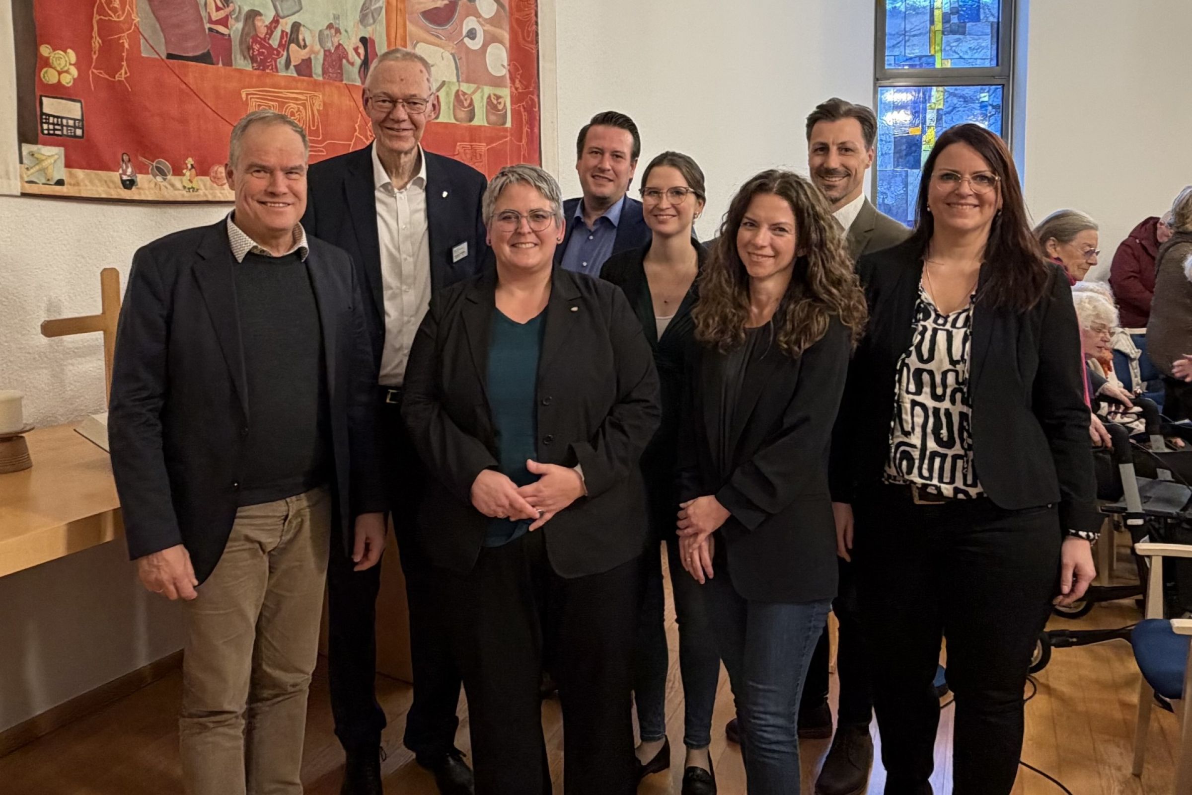 Ein Gruppenbild mit 8 Personen in einem hellen und modernen Altarraum