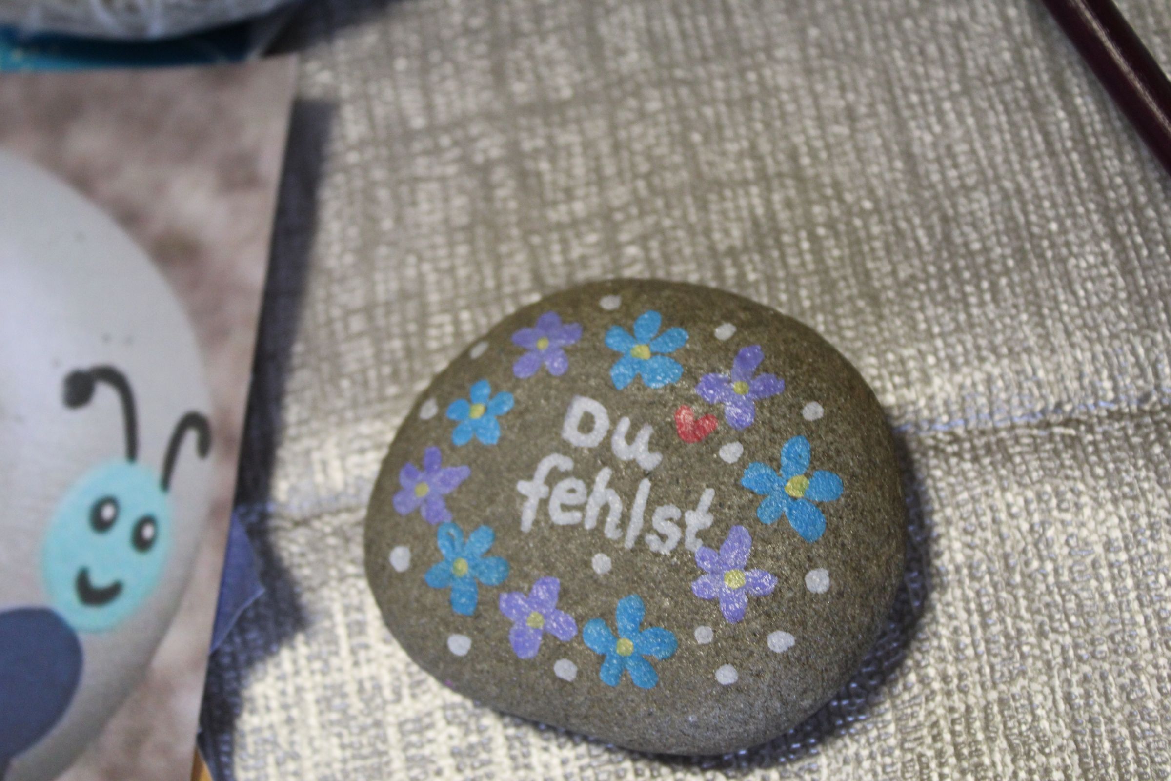 Bemalter Stein auf dem "Du fehlst" steht