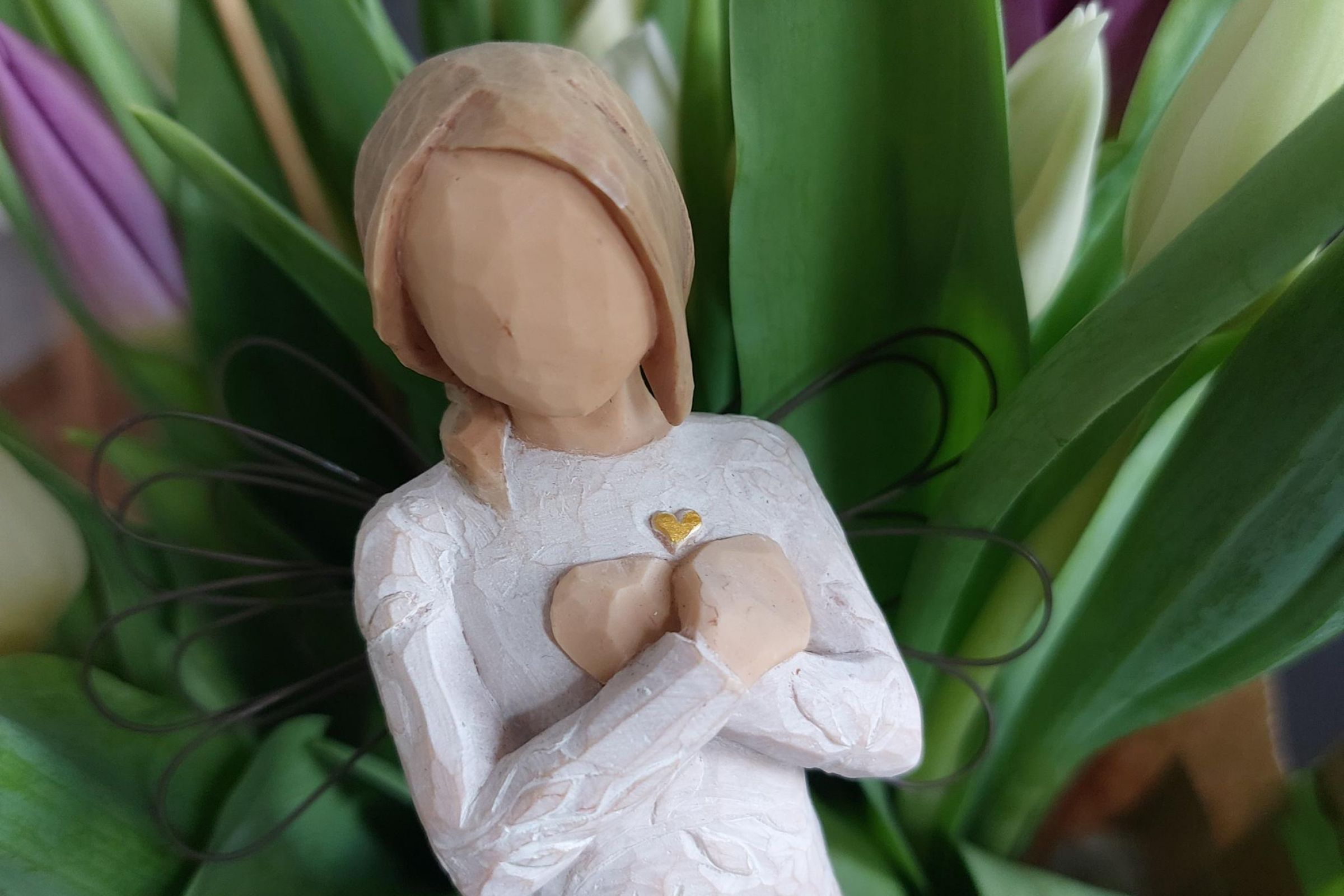 Nahaufnahme eines Holz-Engels mit goldenen Herz