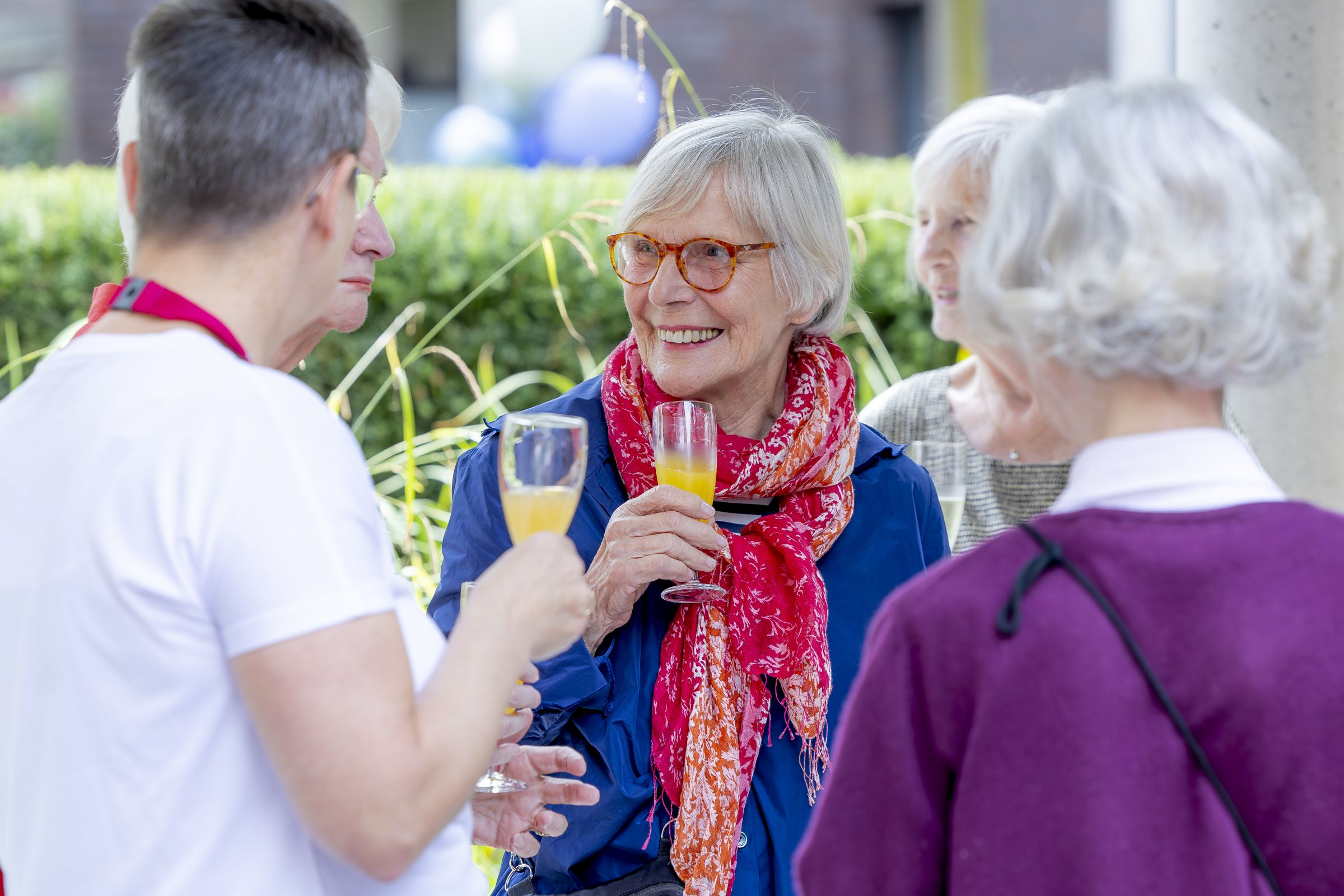 Festgäste im freundlichen Gespräch miteinander, ein Glas Sekt in der Hand