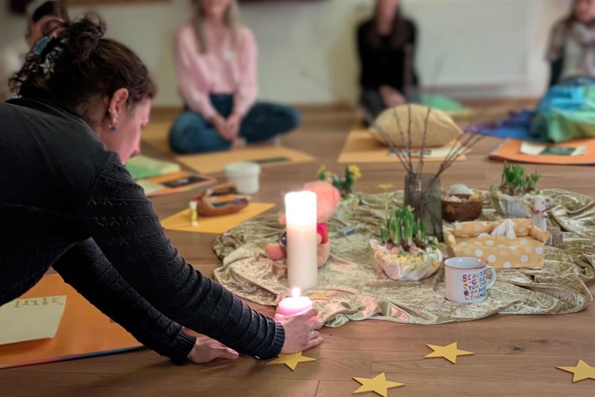 Gruppe von Menschen sitzt im Kreis um eine Kerze