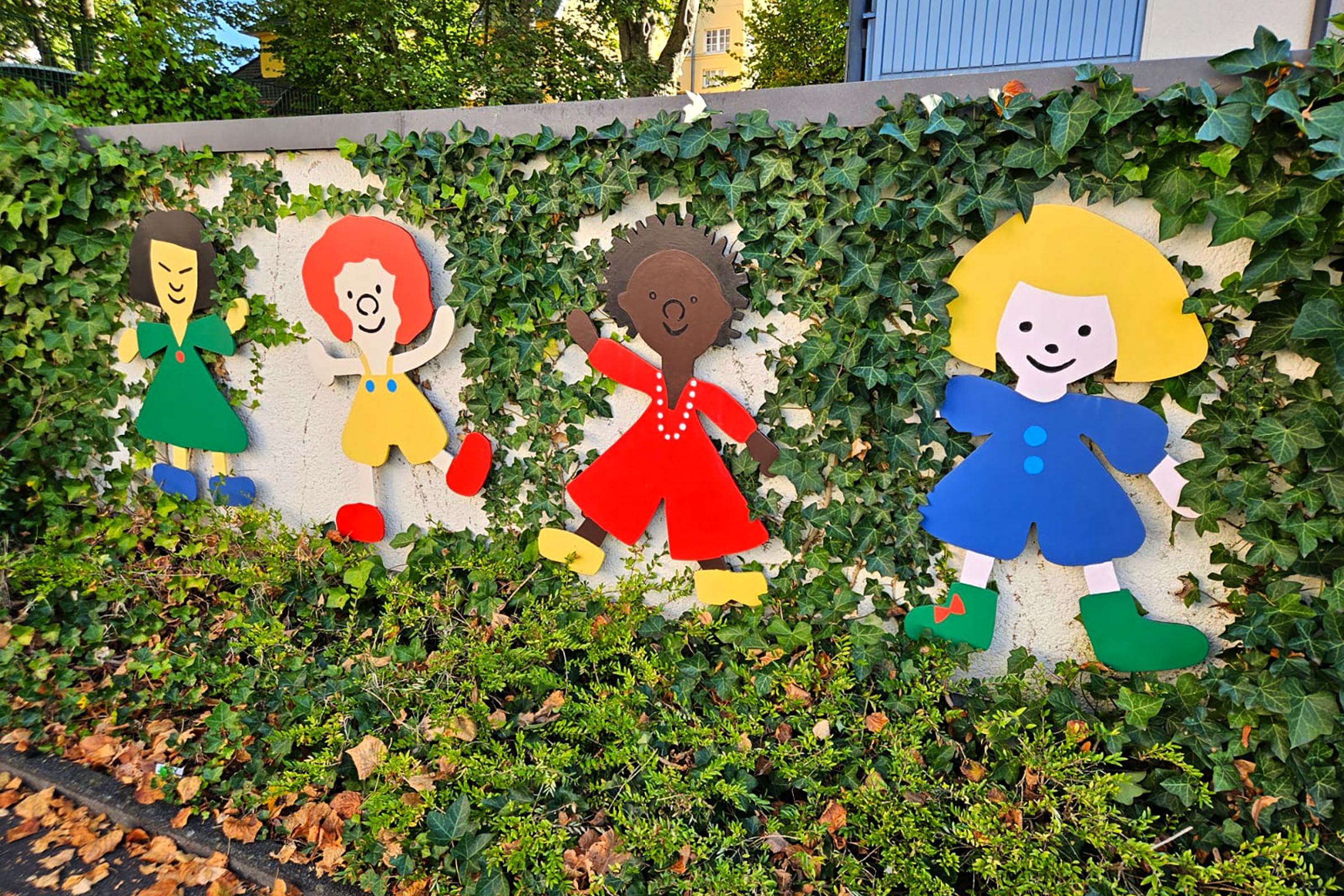 Eine mit Efeu bewachsene Mauer mit Kinderfiguren