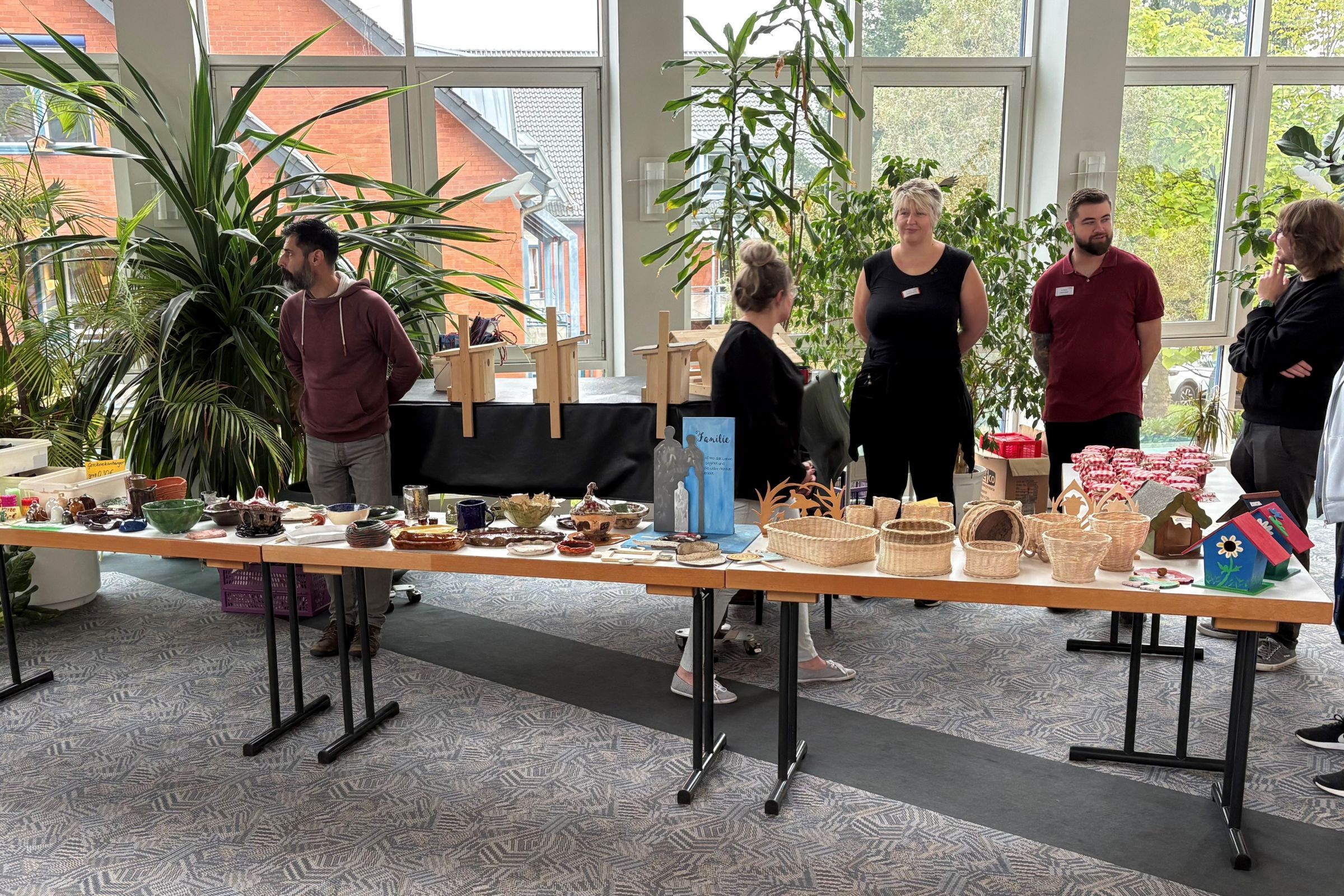 Mitarbeiter der Fachklinik stehen an einem Tisch und bieten Handgemachtes gegen Spende an