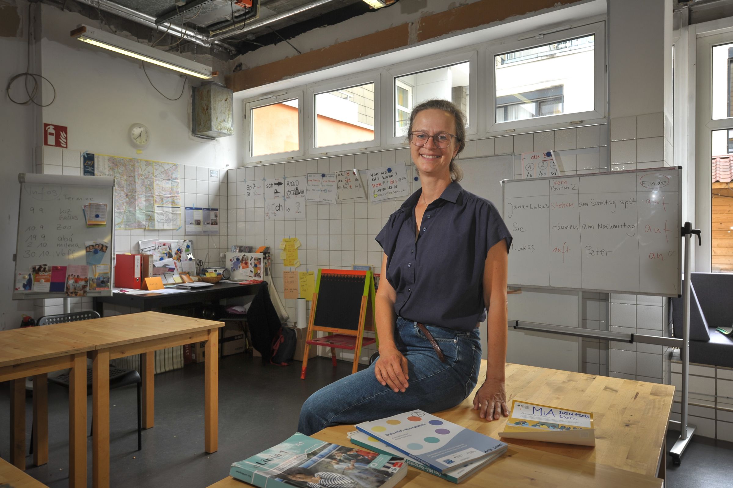 Antje Wooge sitzt auf einem Holztisch im Jugendzentrum und lächelt