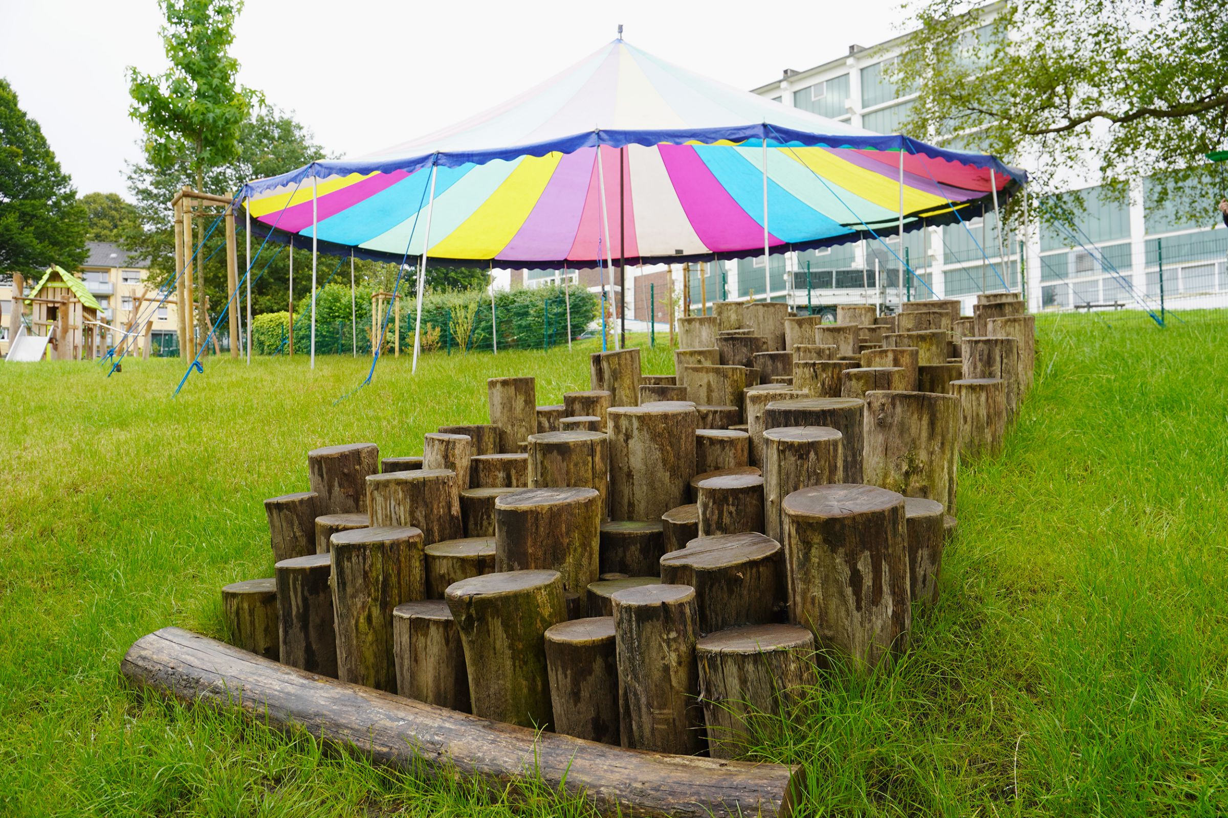 Das Außengelände der Kita mit einer Aufreihung an Baumstämmen in verschiedenen Höhen. 