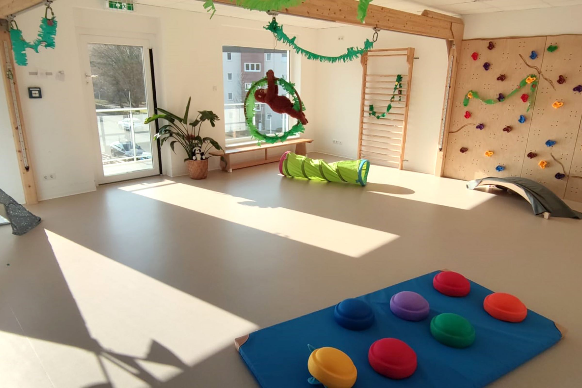 Der Bewegungsraum der Kita mit Kletterwand, Matten und Spielsachen. 