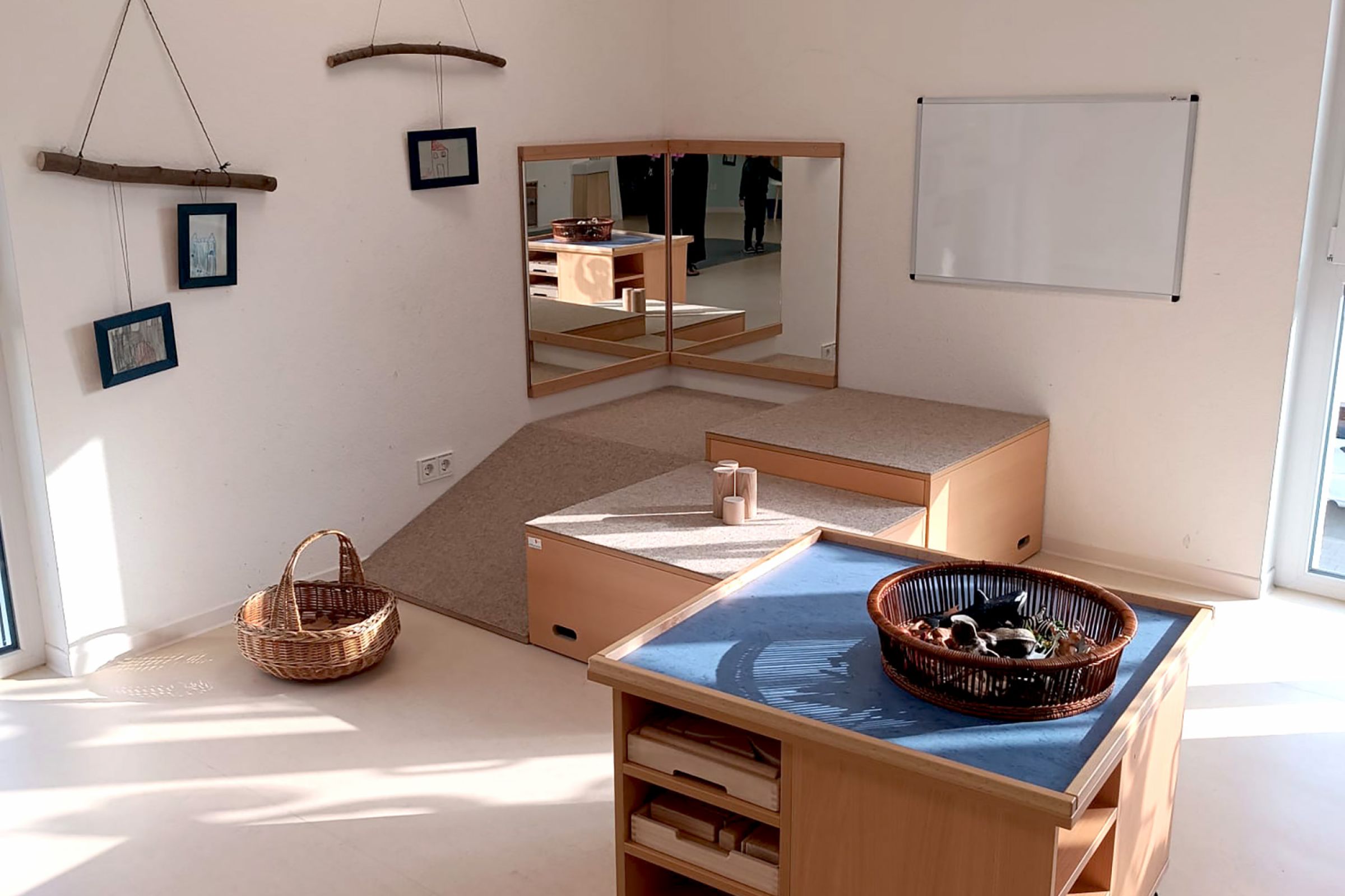 Eine Spielecke in der Kita mit Spiegel, Whiteboard und Bauklötzen in einer Kommode.