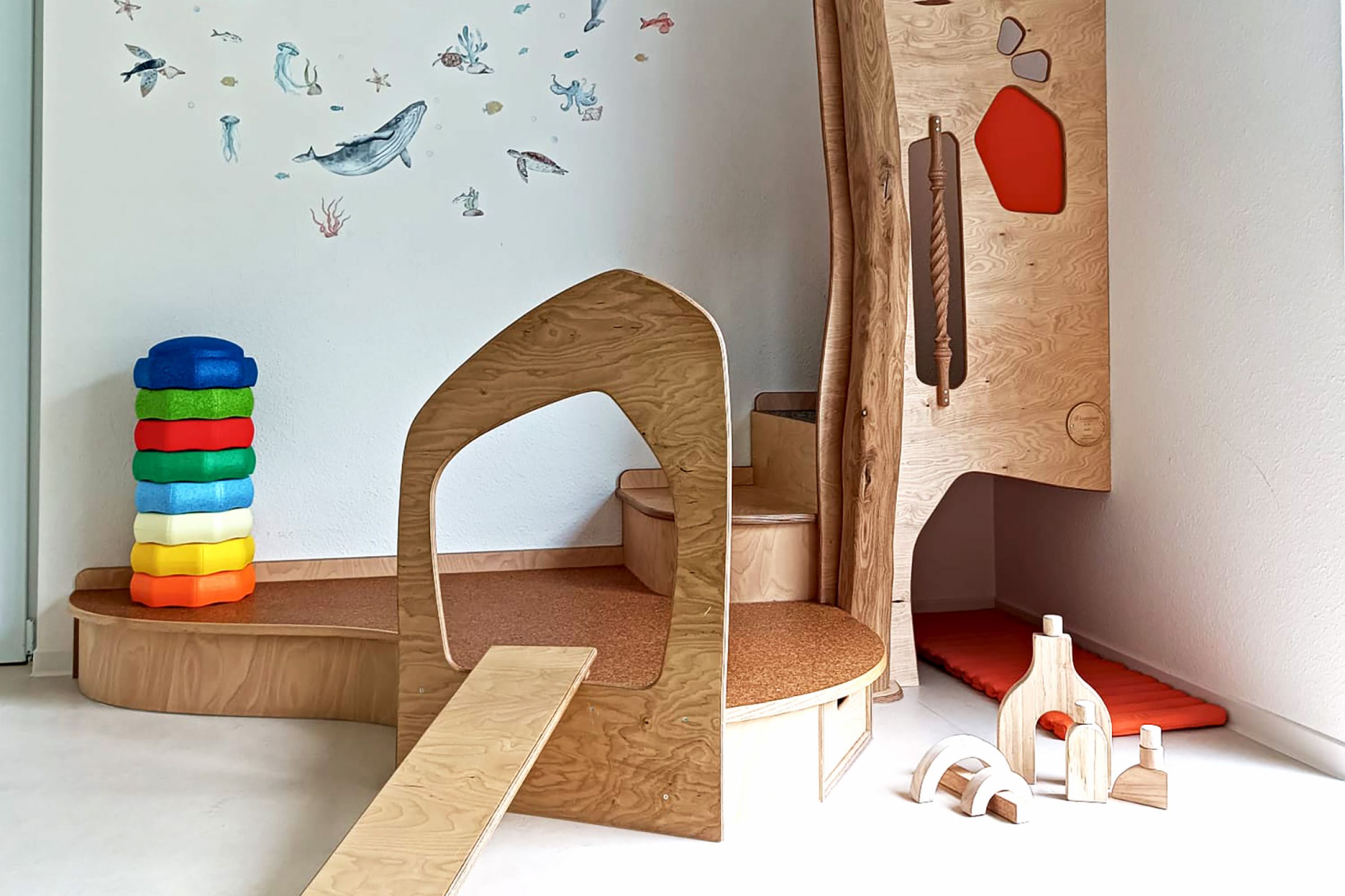 Eine Spielecke in der Kita mit einem kleinen Klettergerüst und Stapelsteinen, die zum spielen einladen. 