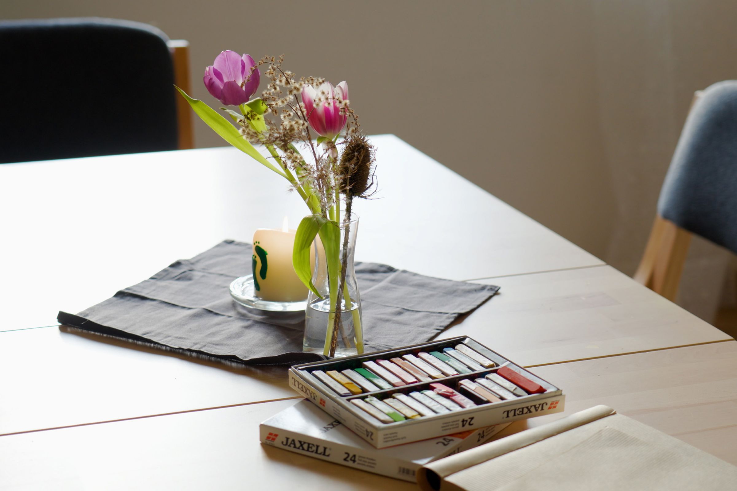 Ein Close-Up einer Blume auf einem Tisch mit Malkreise und einer kleinen Kerze-