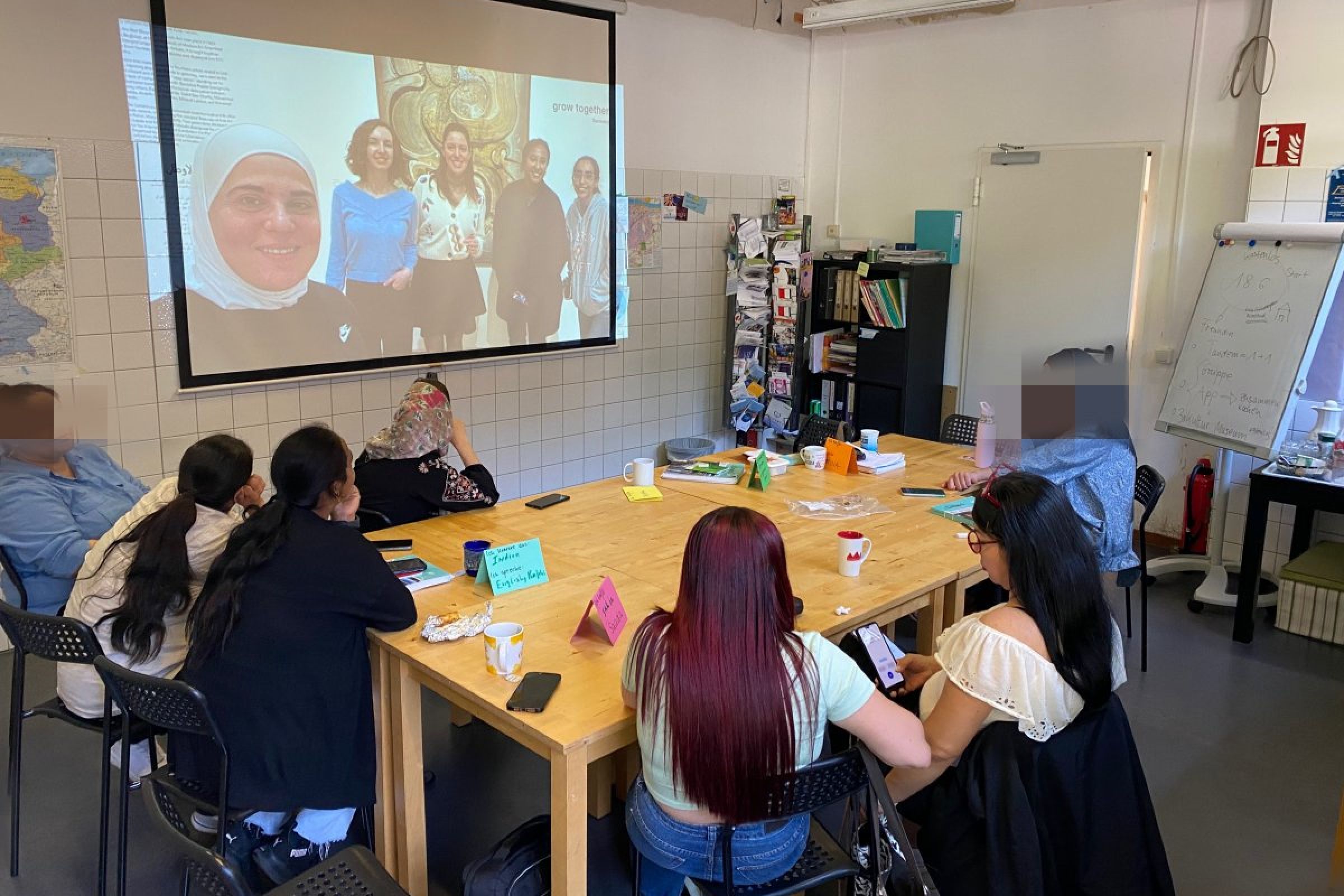 Eine Gruppe von fünf Frauen sitzen rund um einen Holztisch im Jugendzentrum basement26