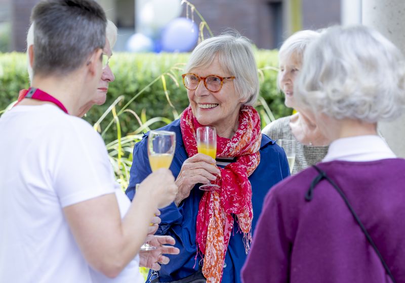 Festgäste im freundlichen Gespräch miteinander, ein Glas Sekt in der Hand