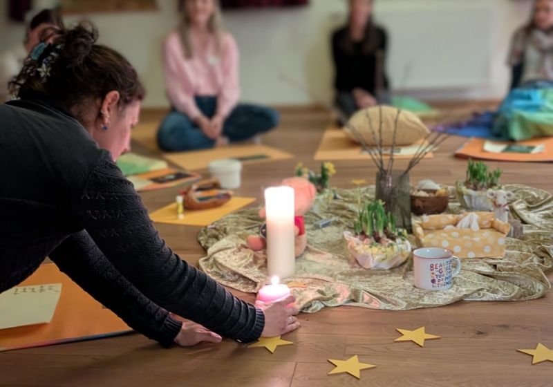 Gruppe von Menschen sitzt im Kreis um eine Kerze