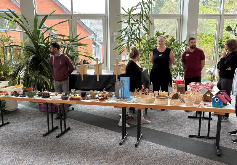Mitarbeiter der Fachklinik stehen an einem Tisch und bieten Handgemachtes gegen Spende an