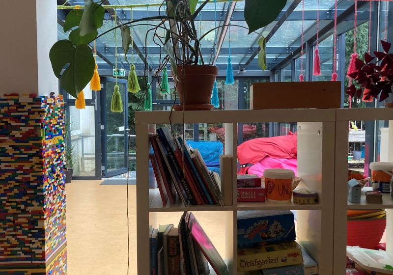 Ein Regal mit Büchern und Pflanzen neben einer bunten Wand